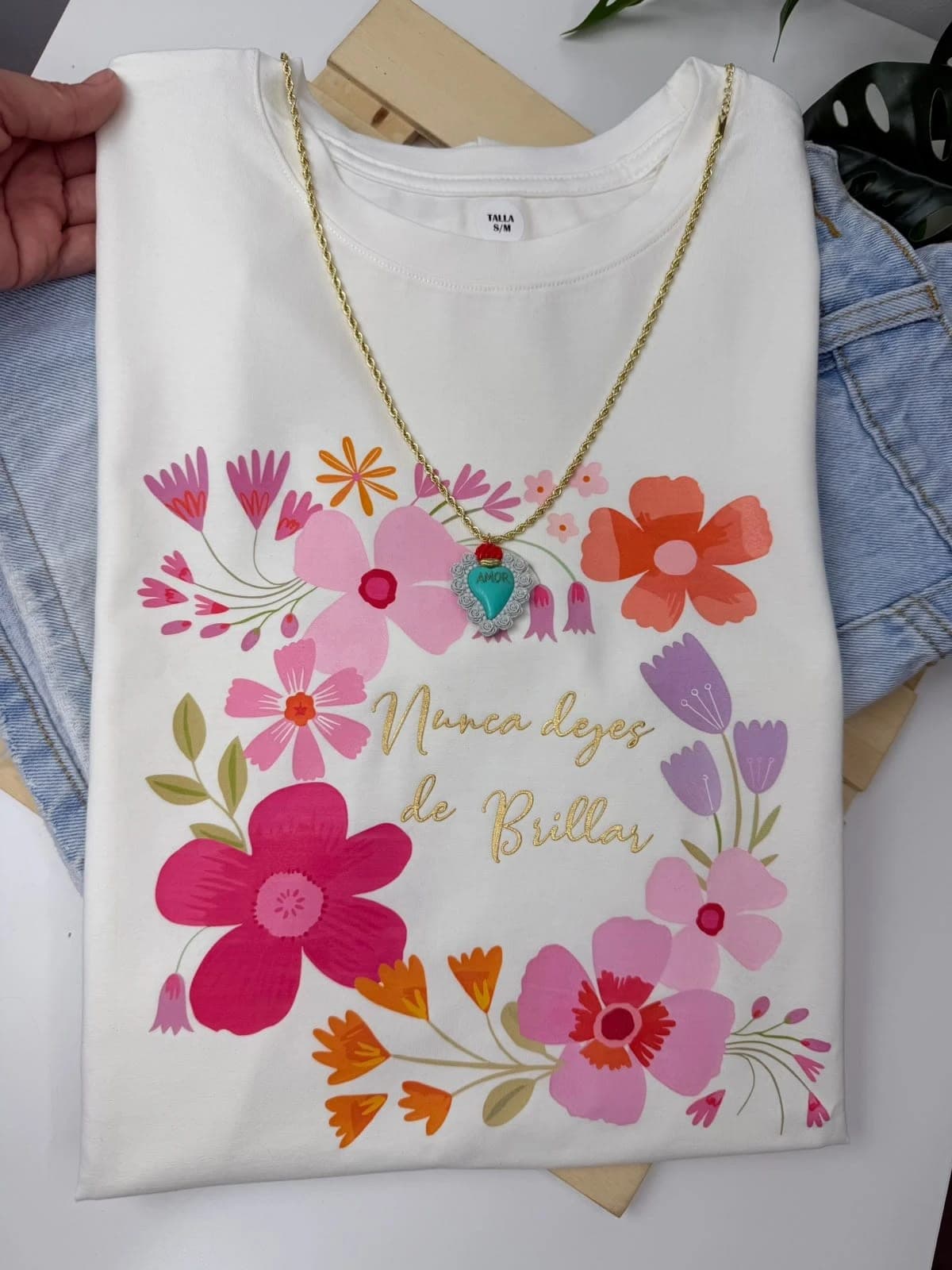Camiseta blanca con flores y la frase Nunca dejes de brillar en dorado